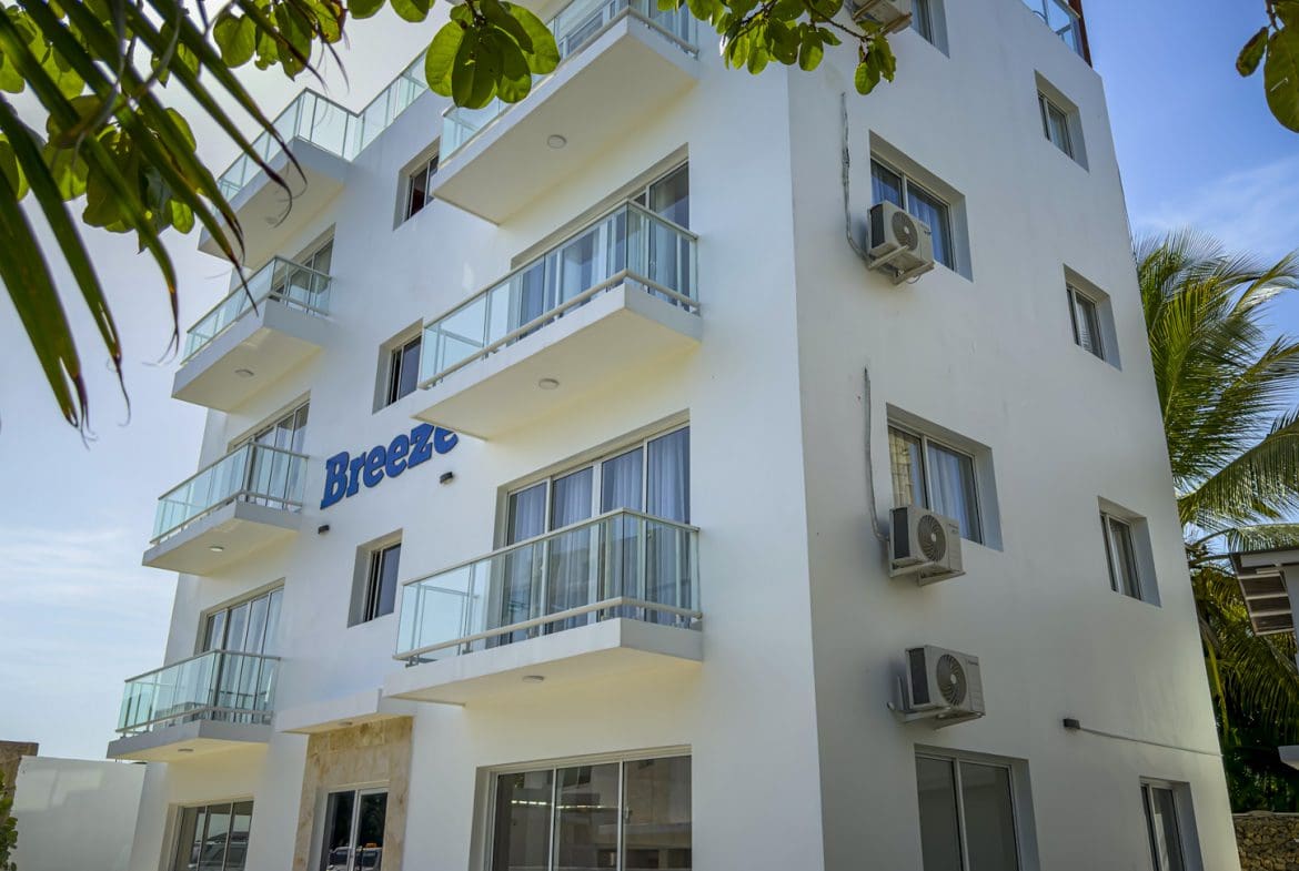 buyDRproperty White building with balconies reads "Breeze". Coastal architecture with air conditioners. Sosua Real Estate