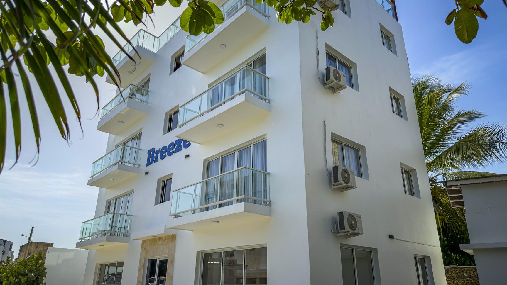 buyDRproperty White building with balconies reads "Breeze". Coastal architecture with air conditioners. Sosua Real Estate