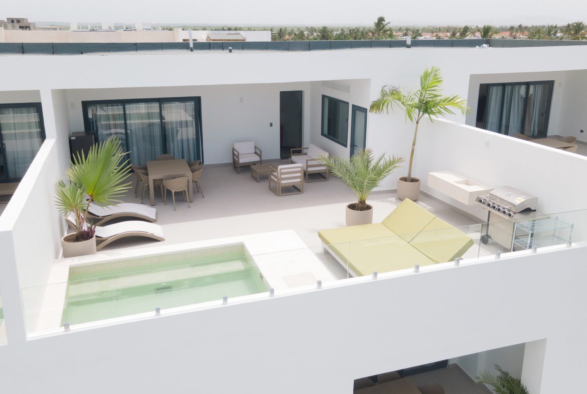 buyDRproperty Rooftop terrace with pool, lounge chairs, dining area, and grill, offering luxury outdoor living. Sosua Real Estate