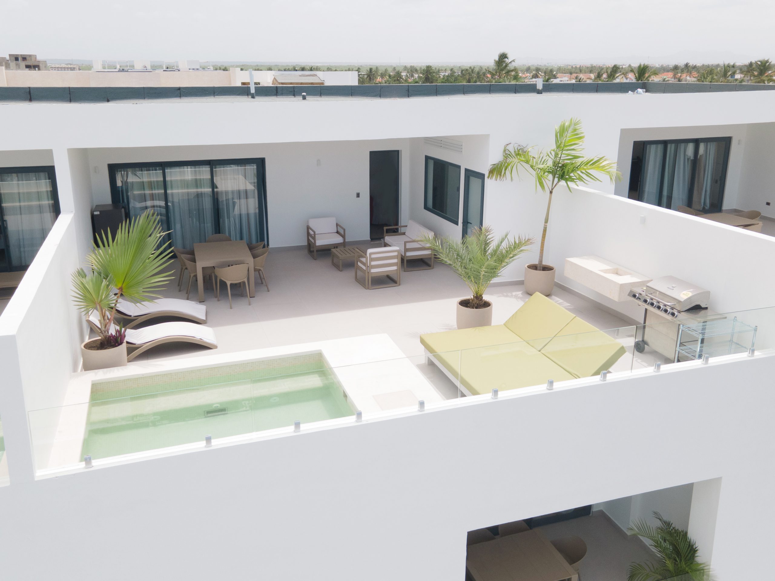buyDRproperty Rooftop terrace with pool, lounge chairs, dining area, and grill, offering luxury outdoor living. Sosua Real Estate