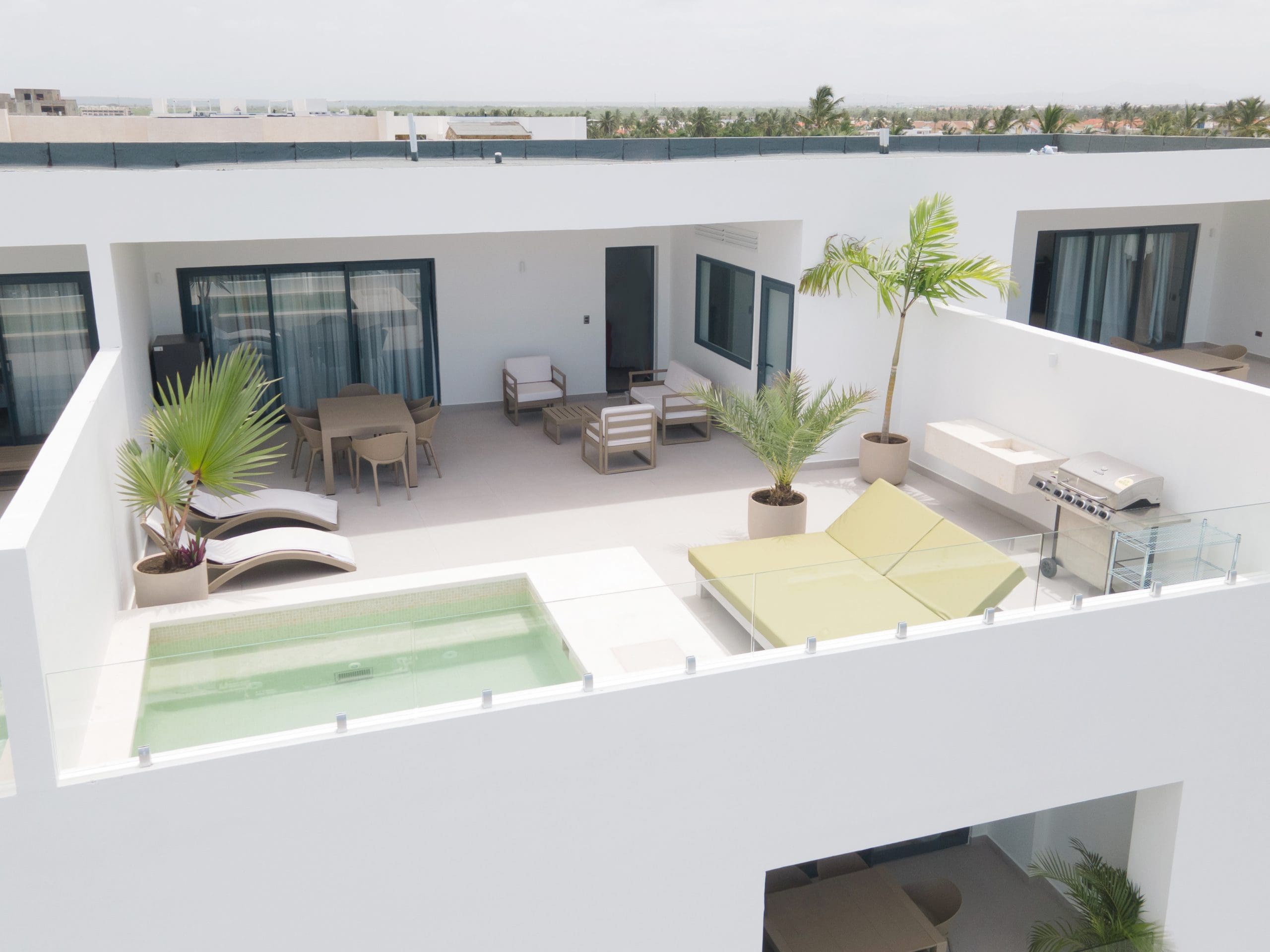 buyDRproperty Rooftop terrace with pool, lounge chairs, dining area, and grill, offering luxury outdoor living. Sosua Real Estate