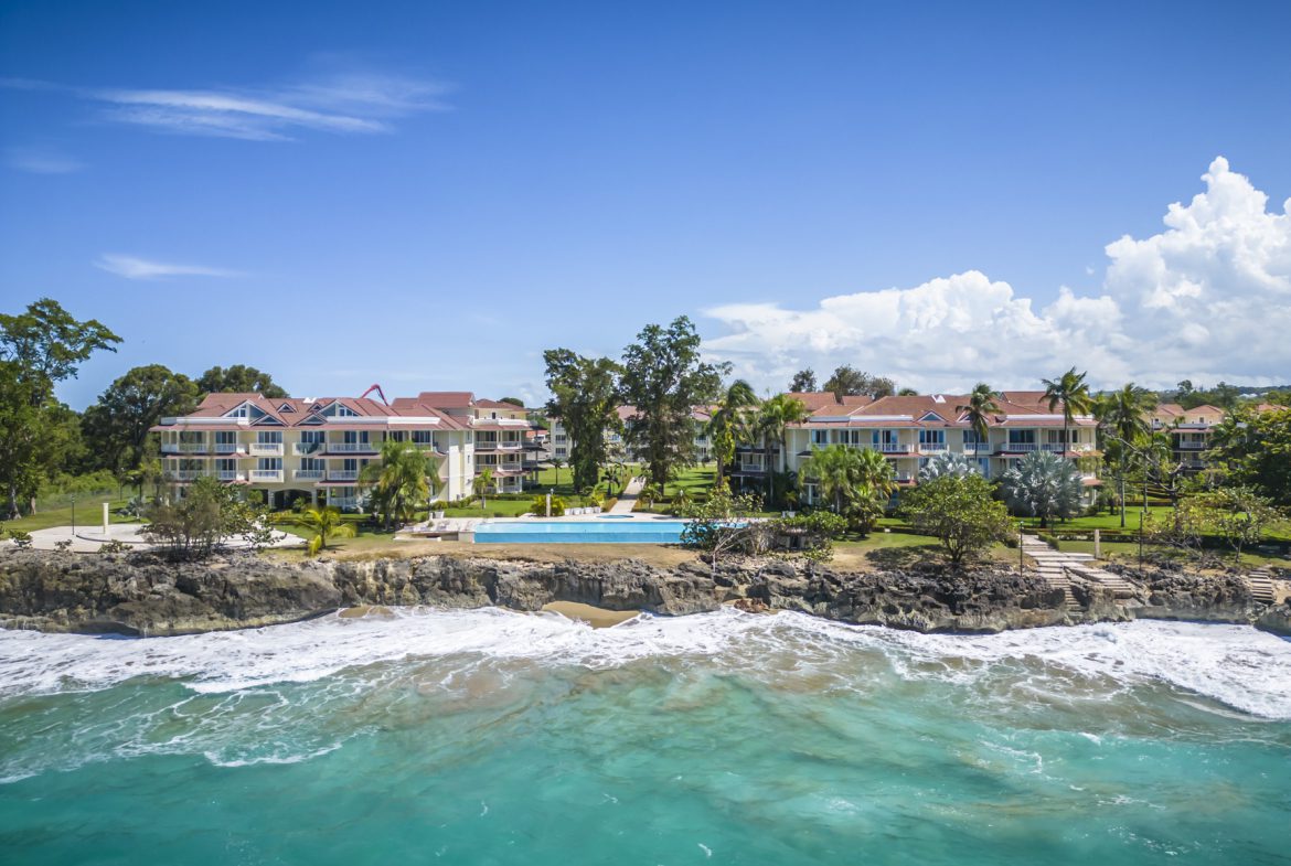 buyDRproperty Oceanfront condos with pool and beautiful turquoise water on a sunny day. Sosua Real Estate