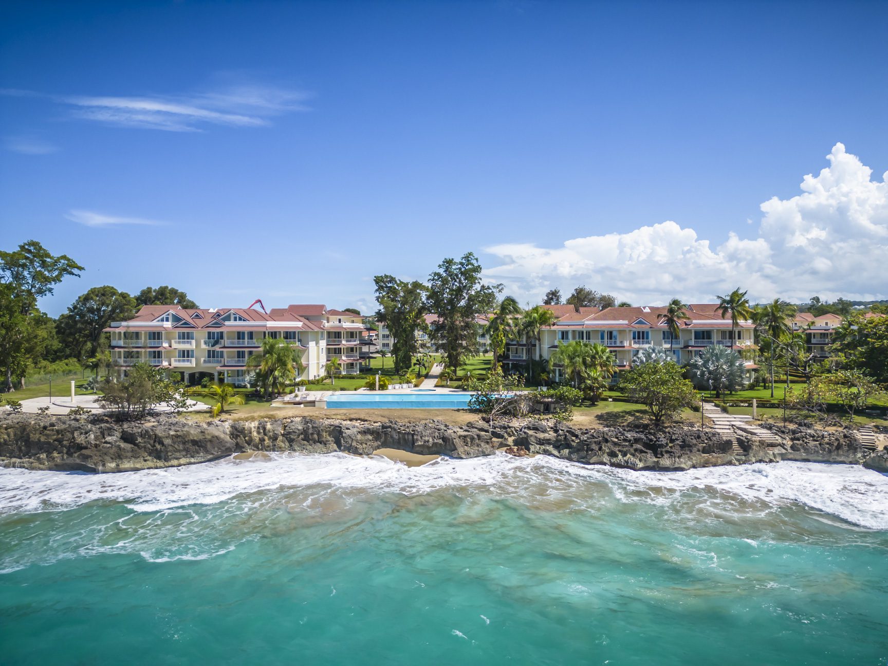 buyDRproperty Oceanfront condos with pool and beautiful turquoise water on a sunny day. Sosua Real Estate