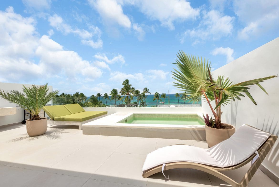 buyDRproperty Rooftop terrace with pool, lounge chairs, and ocean view under a blue sky. Sosua Real Estate
