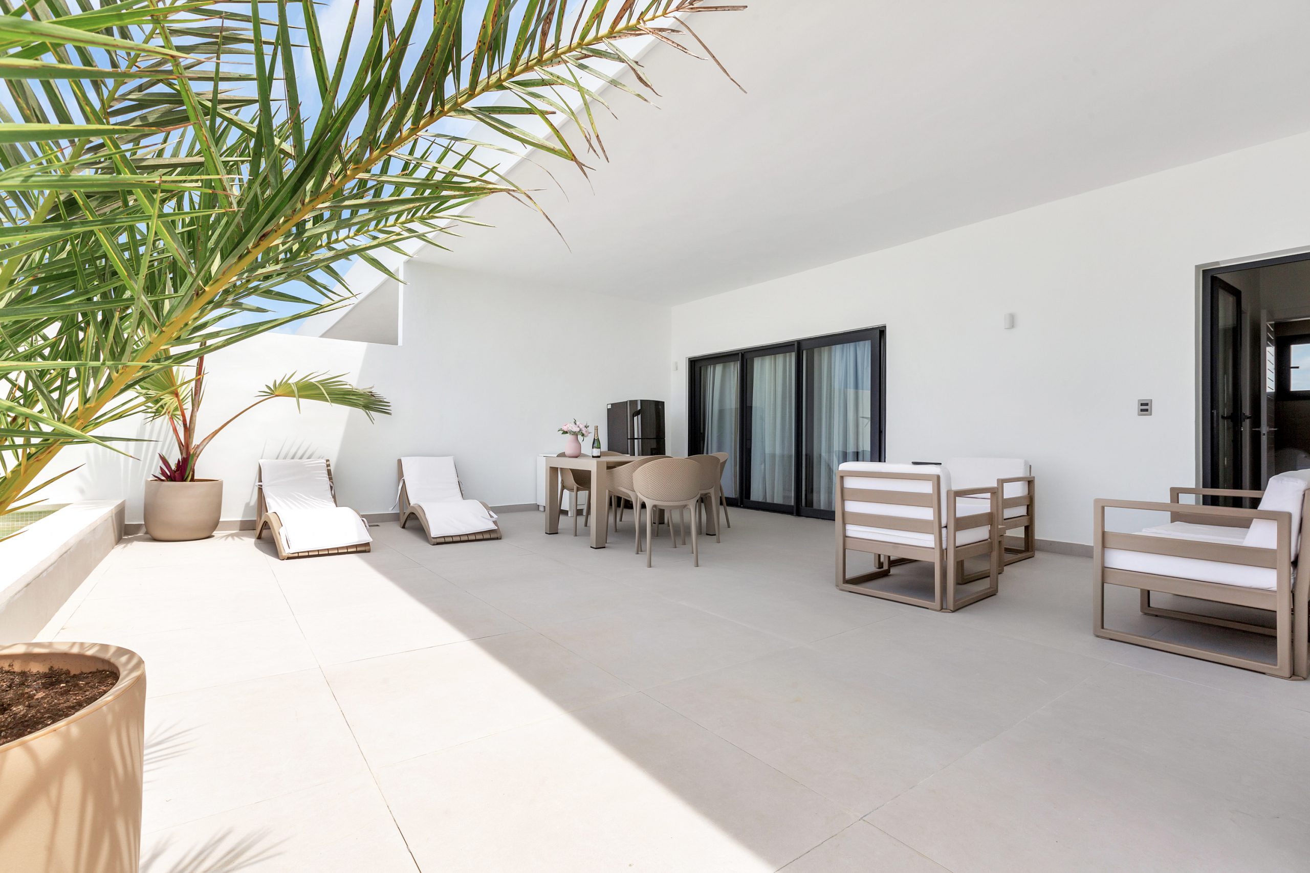 buyDRproperty Modern outdoor patio with seating, dining table, and palm tree. Sosua Real Estate