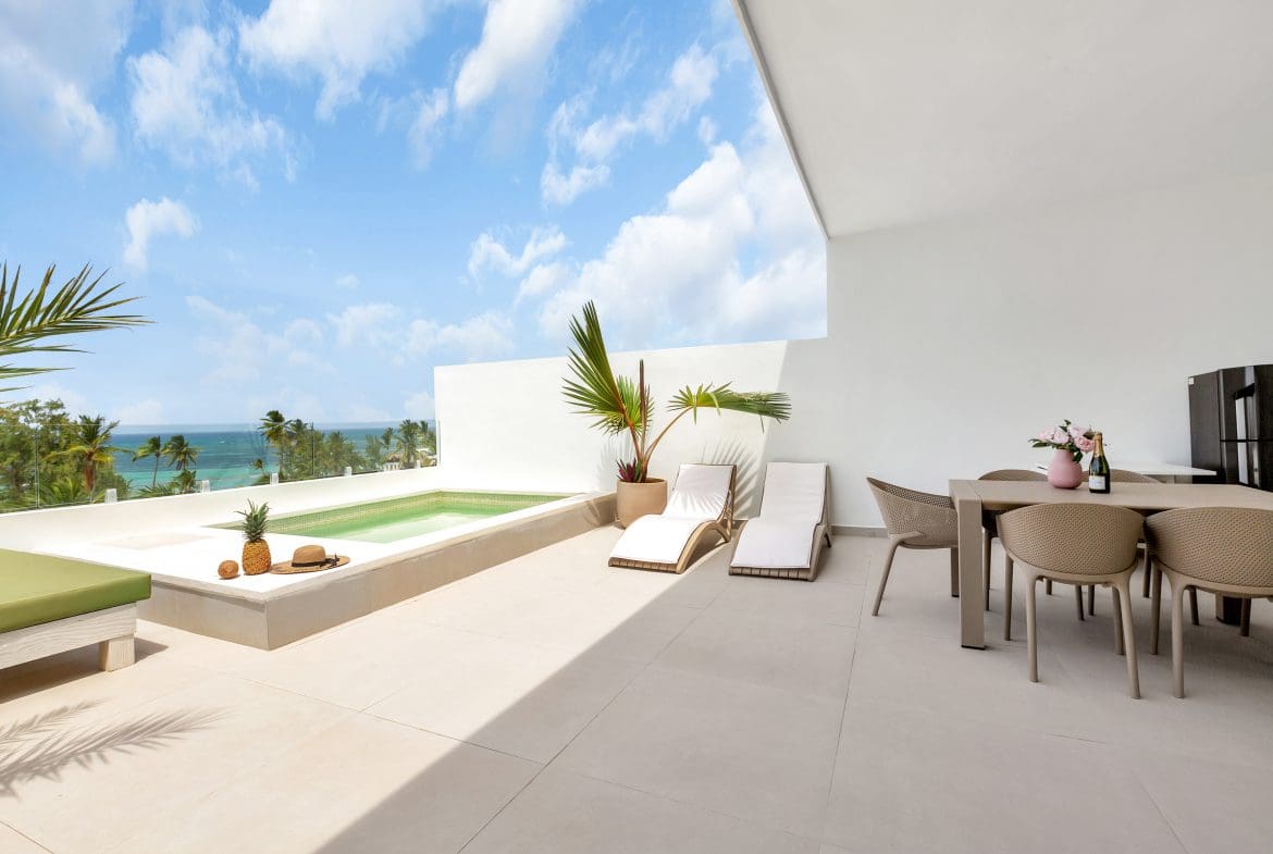 buyDRproperty Luxury balcony with pool, lounge chairs, dining table, and ocean view. Sosua Real Estate