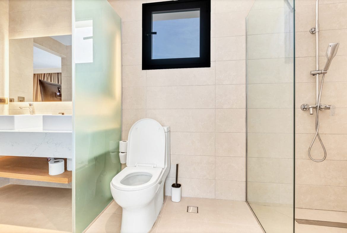 buyDRproperty Modern bathroom: toilet, shower, sink, and window with natural light. Sosua Real Estate