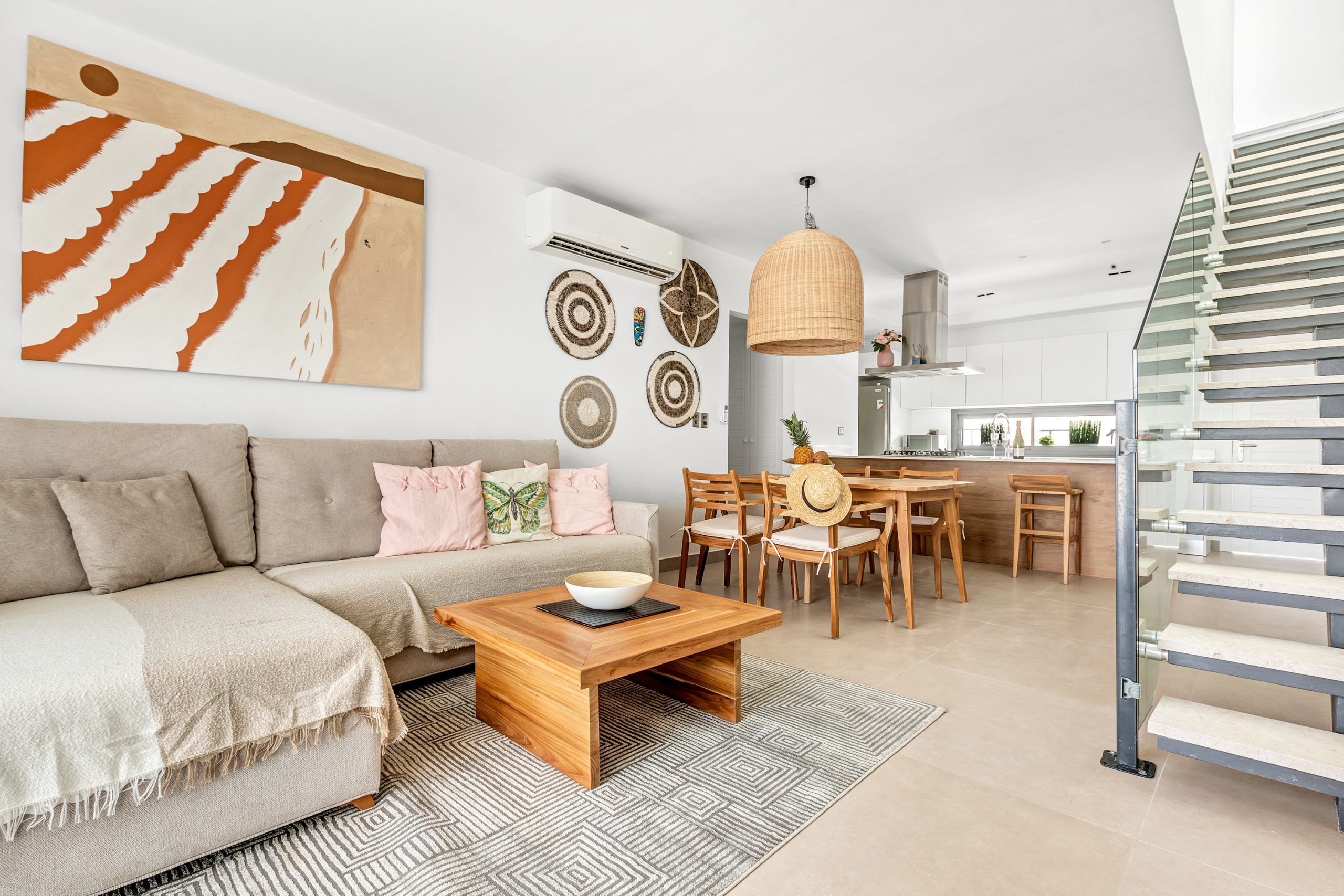 buyDRproperty Bright, modern living room with sofa, dining table, and open kitchen. Neutral tones and natural textures create a relaxed atmosphere. Sosua Real Estate