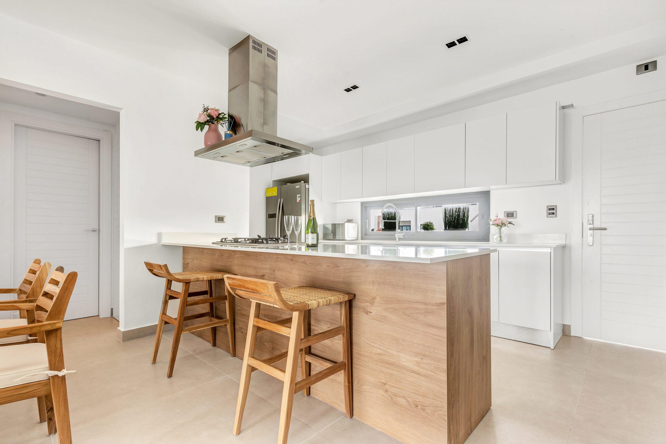 buyDRproperty Modern kitchen with wood island, white cabinets, and stainless steel range hood. Sosua Real Estate