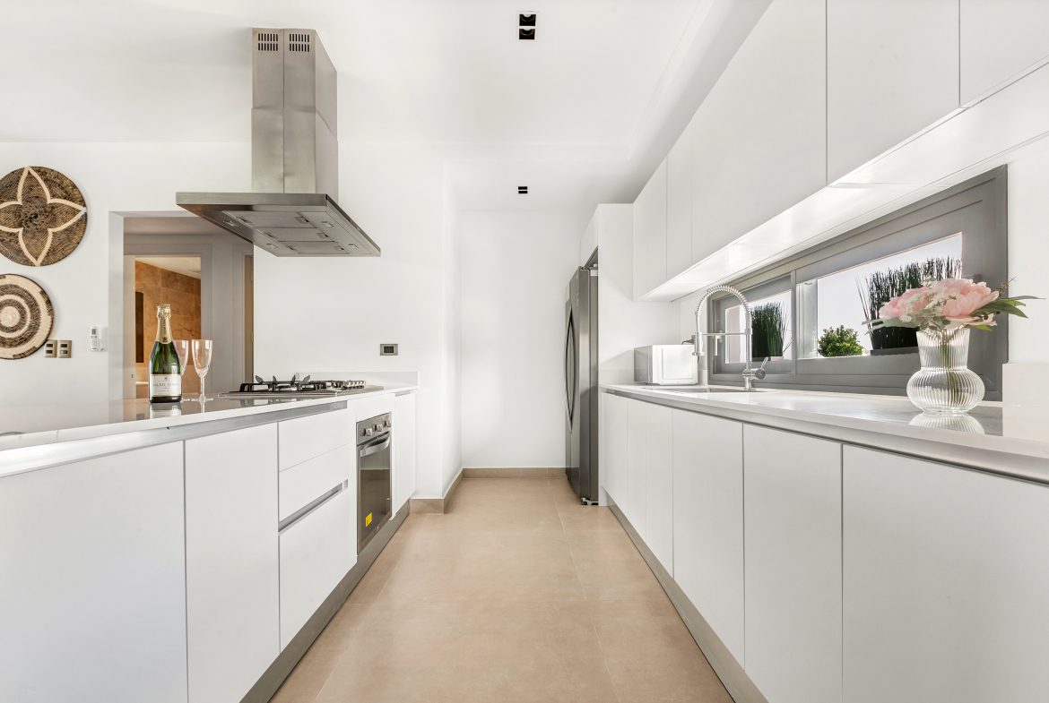 buyDRproperty Bright, modern white kitchen with stainless steel appliances and champagne on the counter. Sosua Real Estate