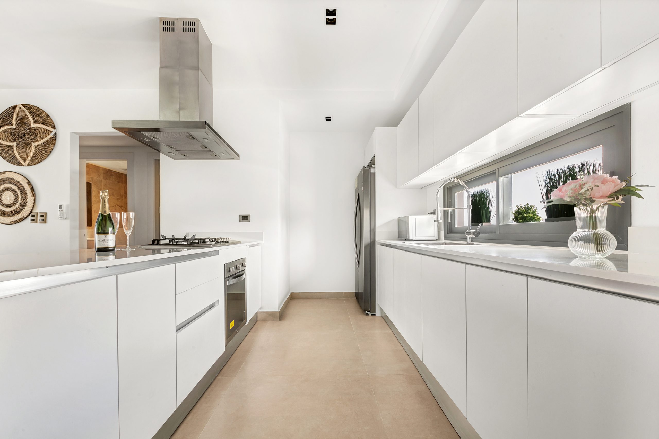 buyDRproperty Bright, modern white kitchen with stainless steel appliances and champagne on the counter. Sosua Real Estate