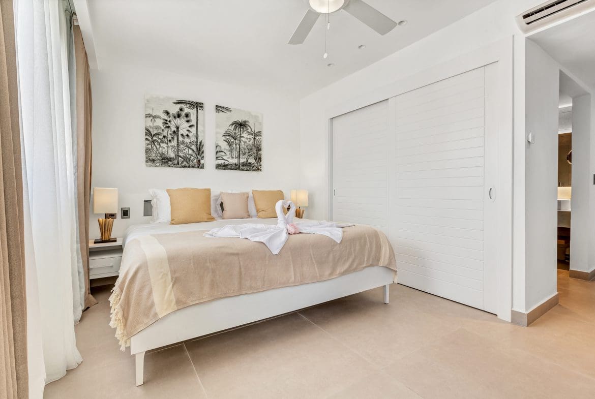 buyDRproperty Bright, modern bedroom with king bed, white linens, and tropical artwork above the headboard. Sosua Real Estate