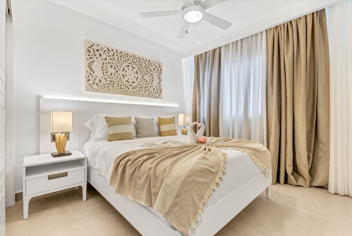 buyDRproperty Bright, modern bedroom with white bed, beige accents, and decorative wall art. Sosua Real Estate