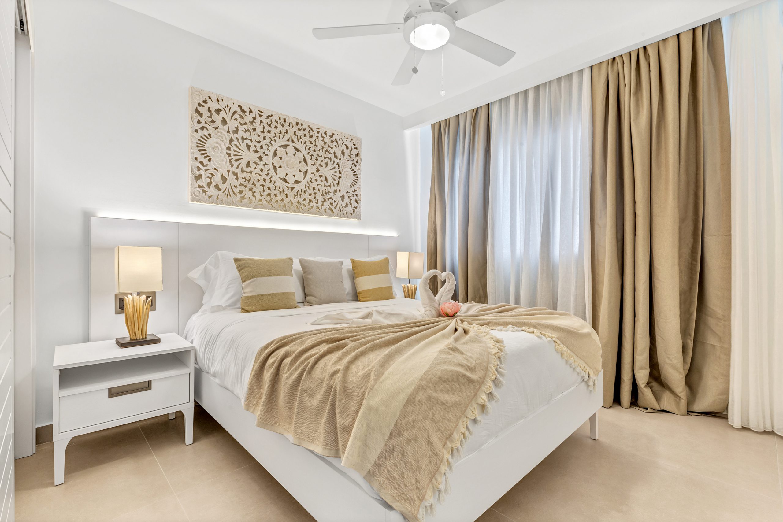 buyDRproperty Bright, modern bedroom with white bed, beige accents, and decorative wall art. Sosua Real Estate