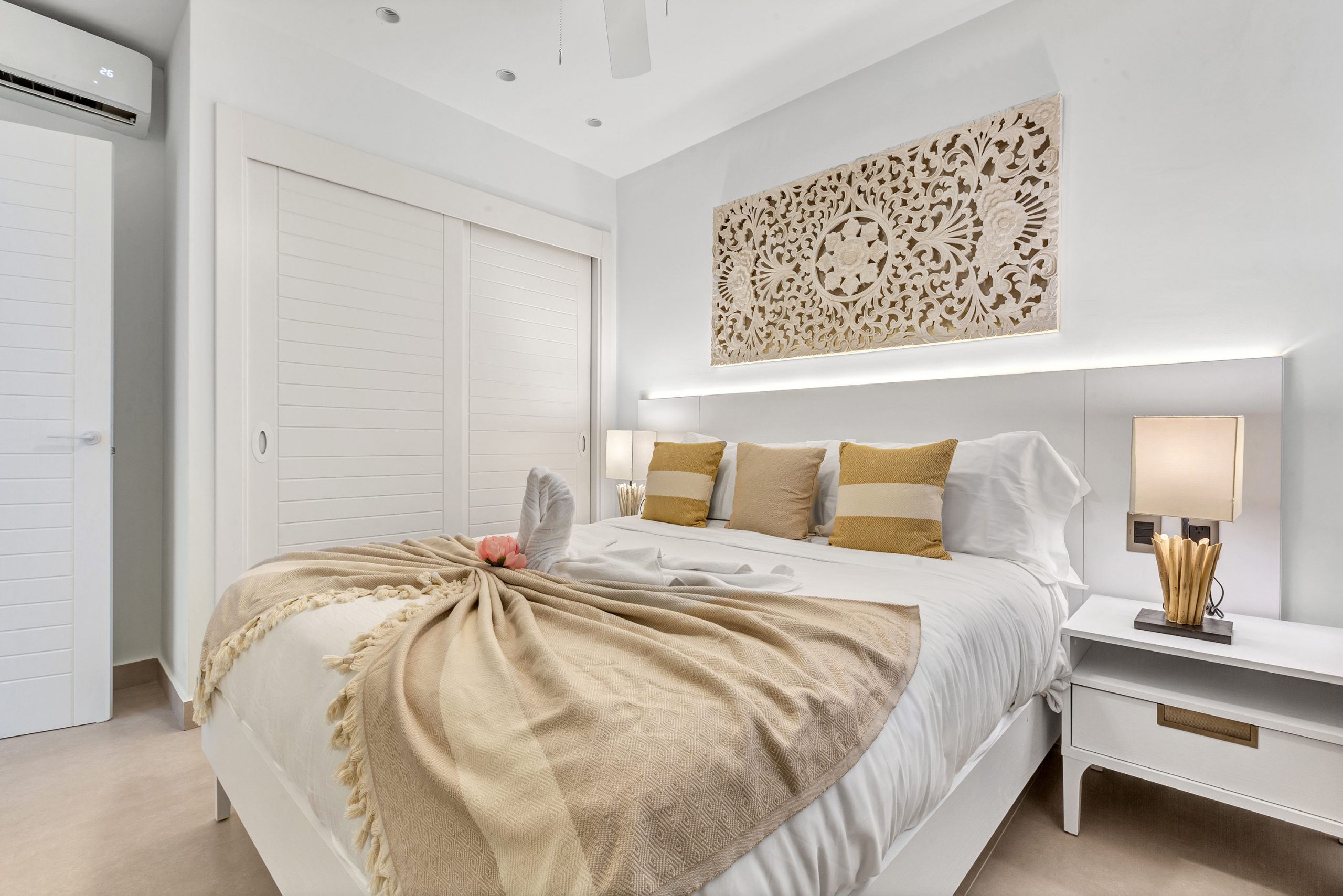 buyDRproperty Bright bedroom with white linens, decorative headboard, and swan towel art on the bed. Sosua Real Estate