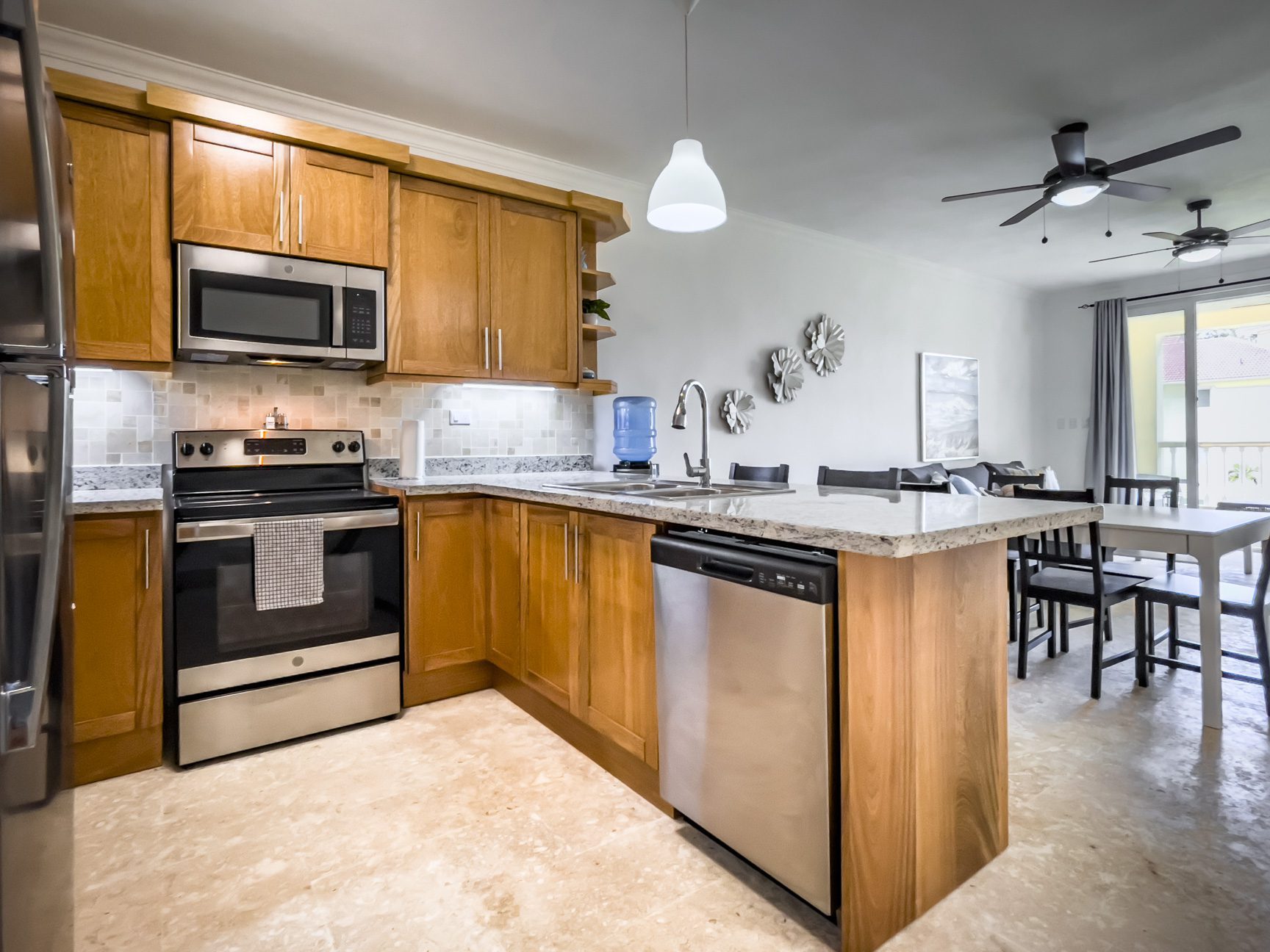buyDRproperty Bright kitchen with wood cabinets, stainless steel appliances, and an island. Dining area visible. Sosua Real Estate