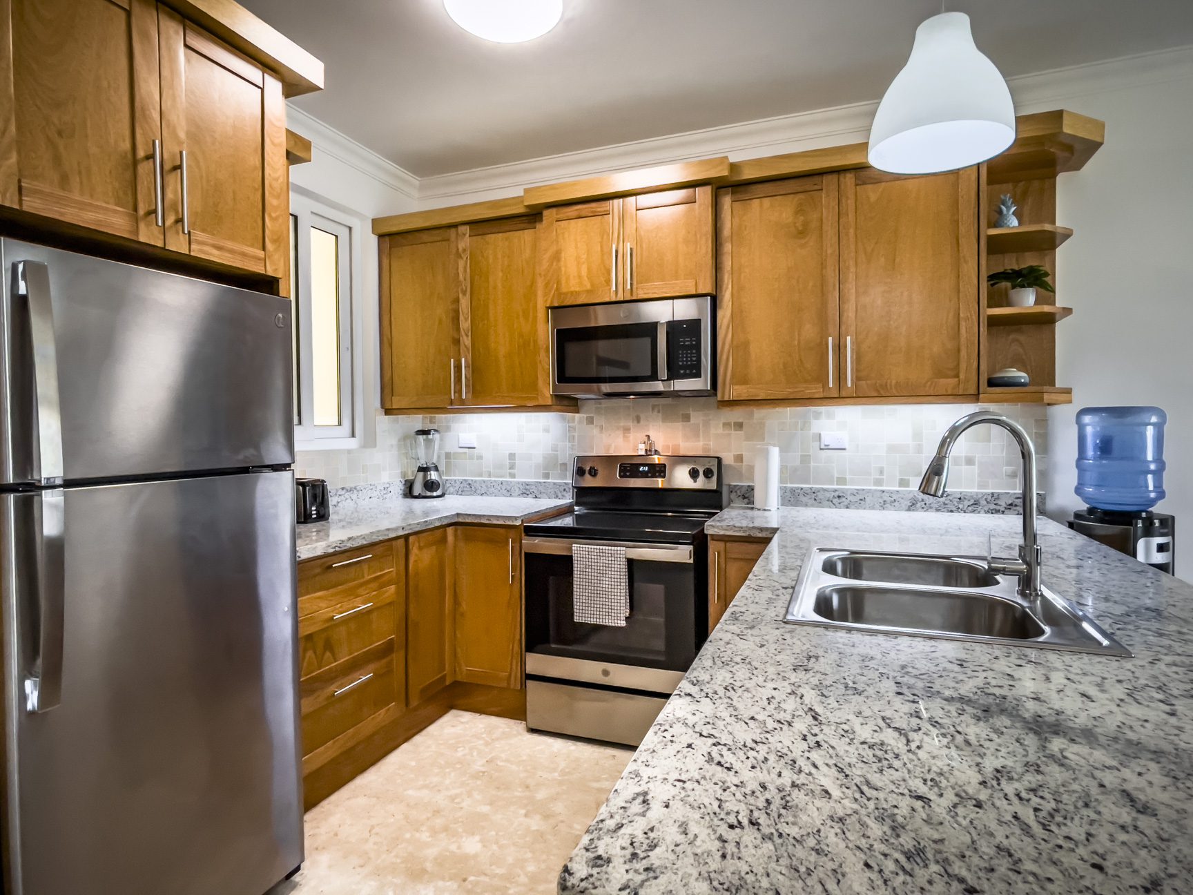 buyDRproperty Modern kitchen with stainless steel appliances, granite countertops, and wooden cabinets. Sosua Real Estate