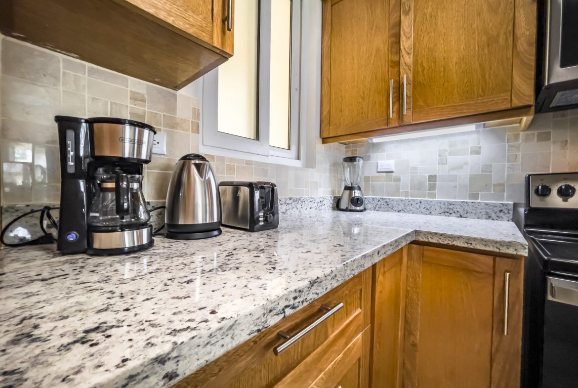 buyDRproperty Kitchen with granite countertops, wood cabinets, coffee maker, toaster, and stainless steel appliances. Sosua Real Estate