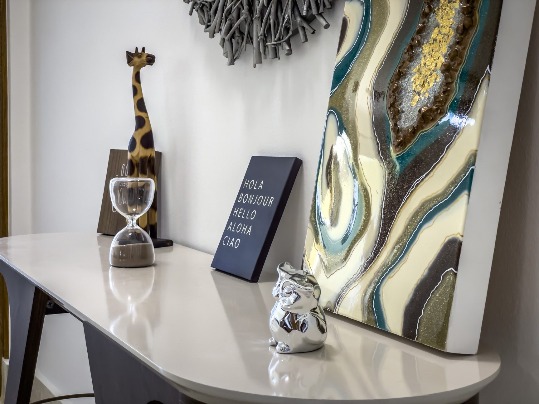 buyDRproperty Stylish console table with decor: giraffe, hourglass, art, and a "Hola Bonjour Hello Aloha Ciao" sign. Sosua Real Estate