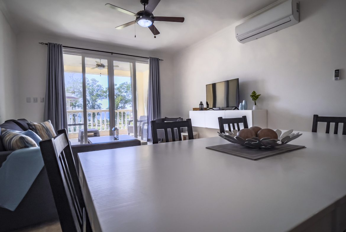 buyDRproperty Bright living and dining area with patio doors leading to a balcony. Modern interior design. Sosua Real Estate