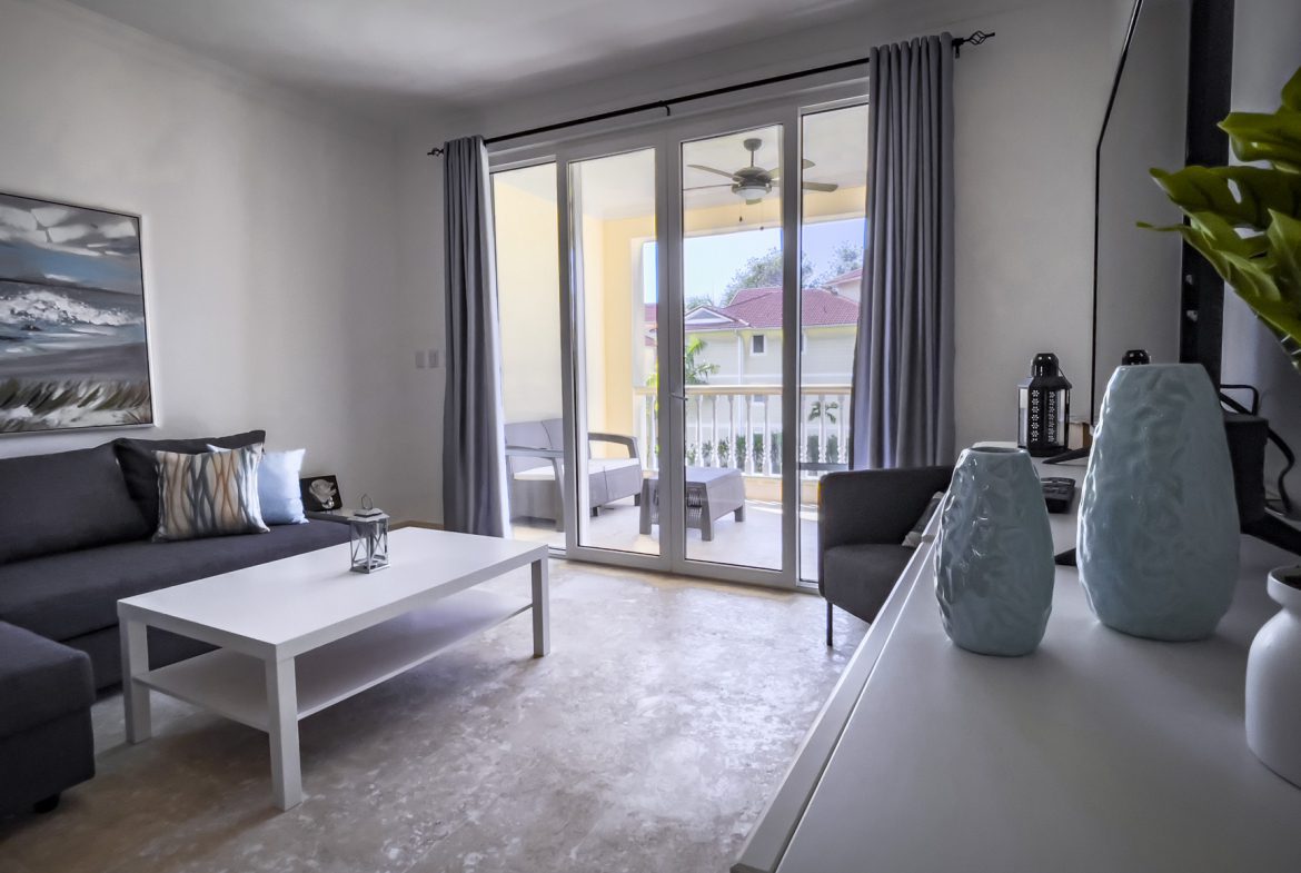 buyDRproperty Bright living room with balcony access, gray sofa, and white coffee table. Sosua Real Estate