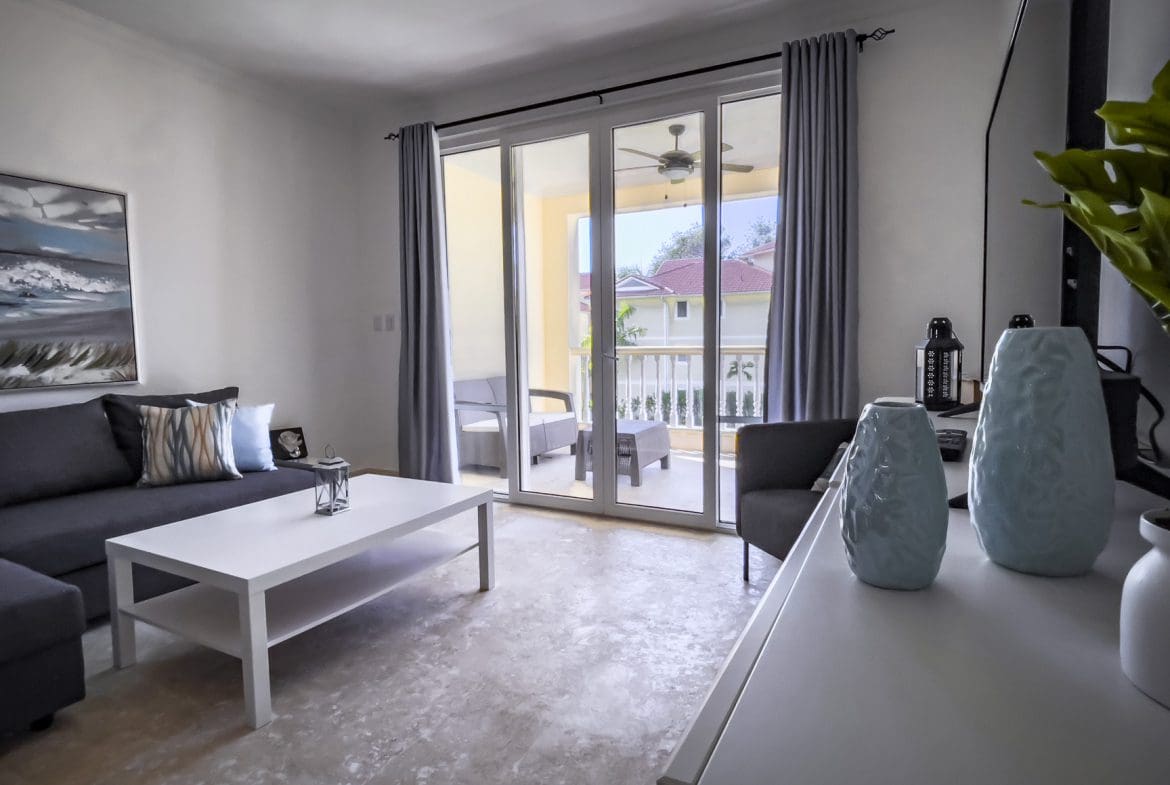 buyDRproperty Bright living room with balcony access, gray sofa, and white coffee table. Sosua Real Estate