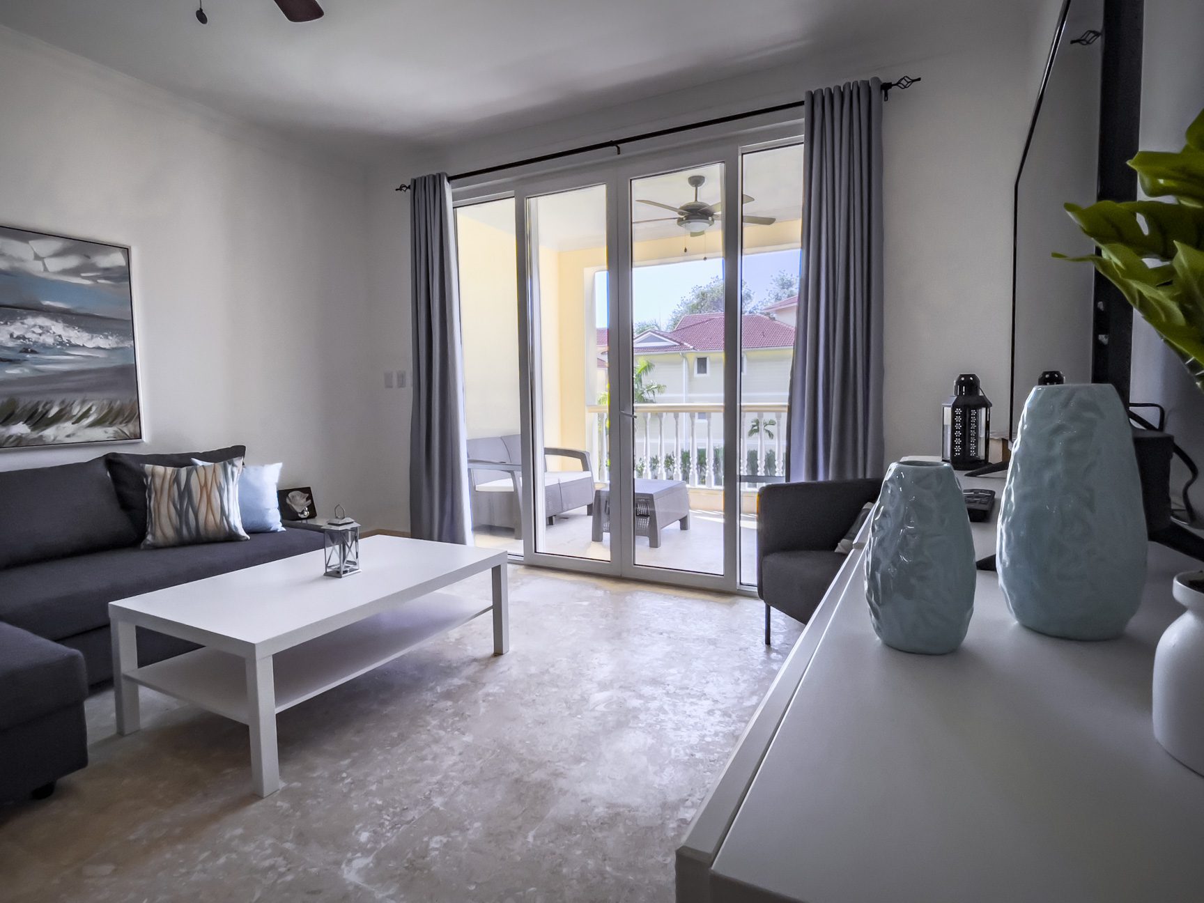 buyDRproperty Bright living room with balcony access, gray sofa, and white coffee table. Sosua Real Estate
