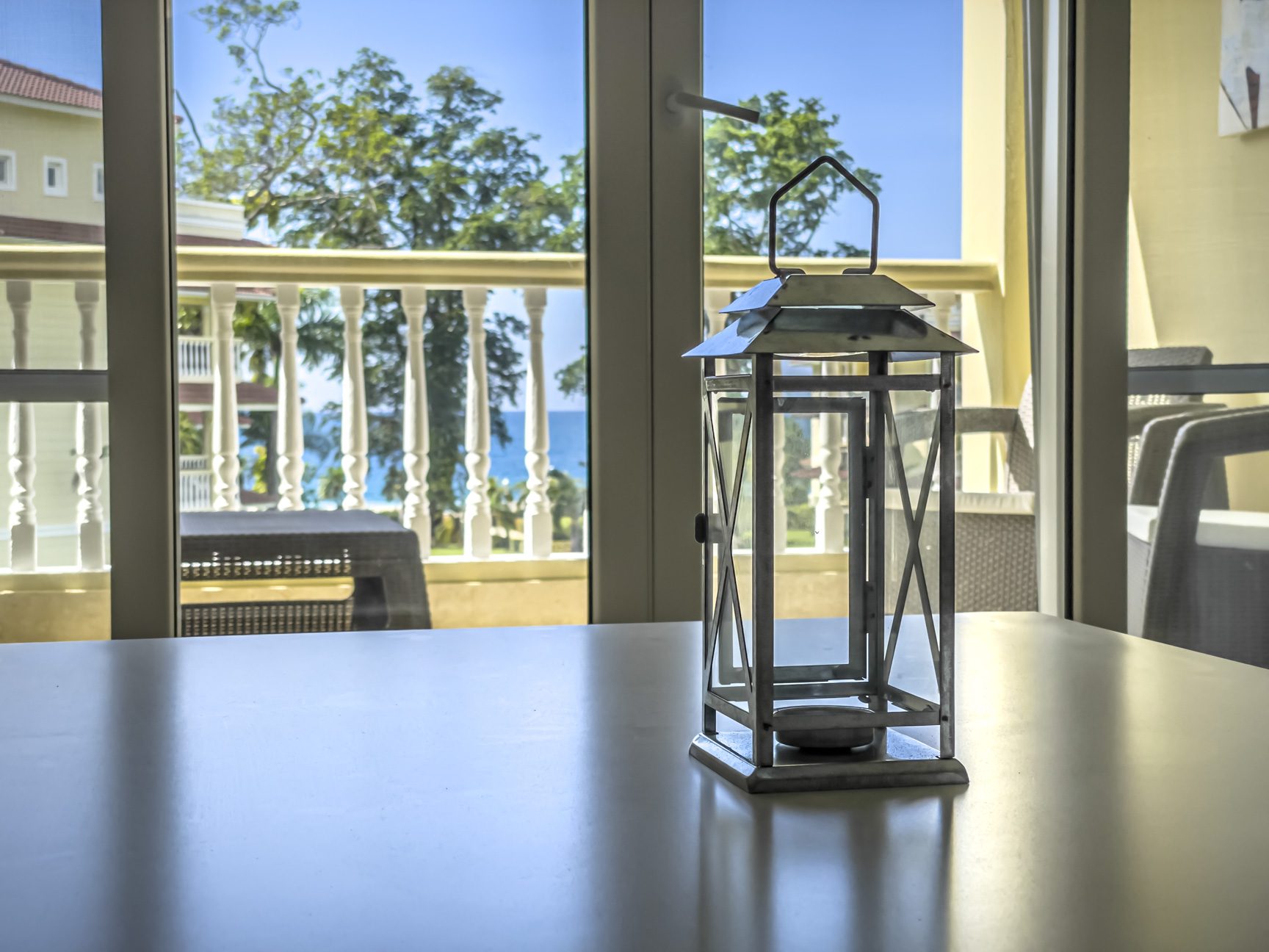 buyDRproperty Lantern on a table with balcony view of ocean and tropical trees. Sosua Real Estate