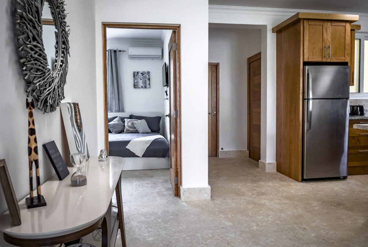 buyDRproperty Apartment interior: bedroom view from hallway, stainless steel fridge, modern decor. Sosua Real Estate