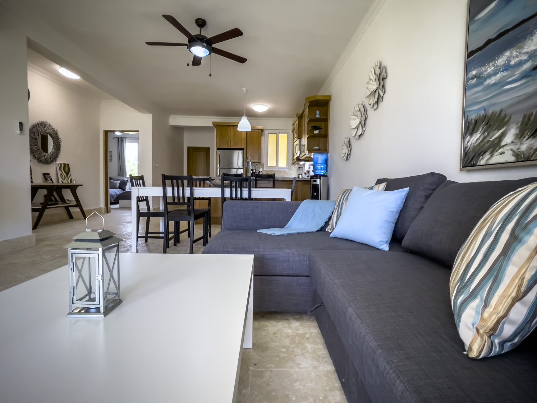 buyDRproperty Living room with gray sectional sofa, white coffee table, and open kitchen in background. Sosua Real Estate