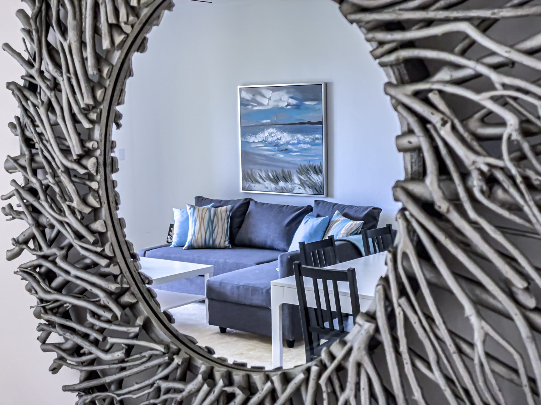 buyDRproperty Cozy living room reflected in driftwood mirror with blue couch and beach painting. Sosua Real Estate