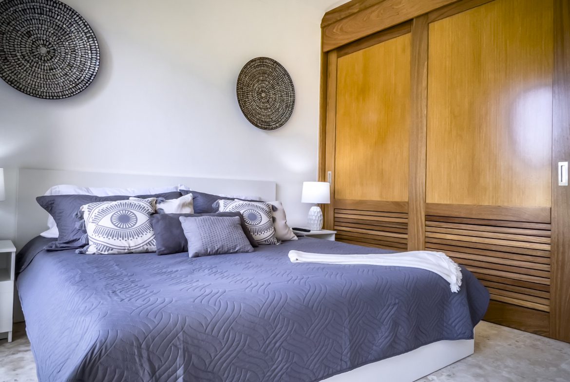 buyDRproperty Relaxing bedroom decor with gray bedding, decorative wall baskets, and wood closet. Sosua Real Estate