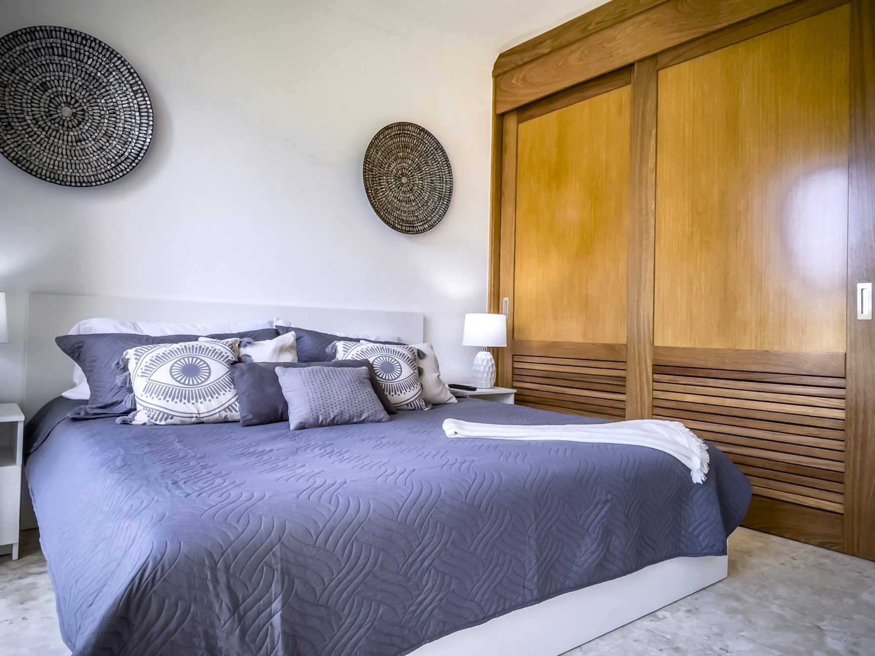 buyDRproperty Relaxing bedroom decor with gray bedding, decorative wall baskets, and wood closet. Sosua Real Estate