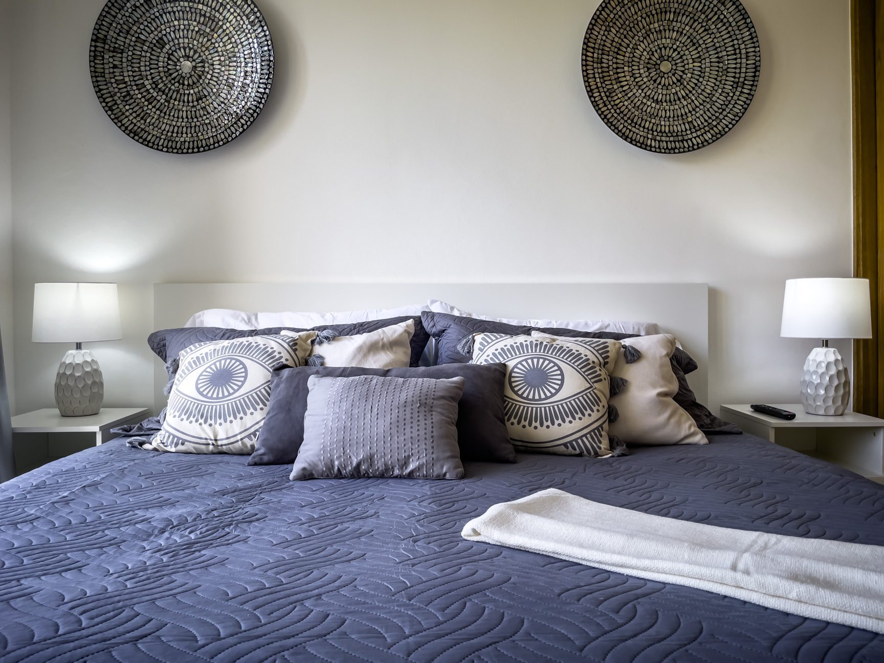 buyDRproperty Cozy bedroom with blue quilt, decorative pillows, and wall art. Sosua Real Estate