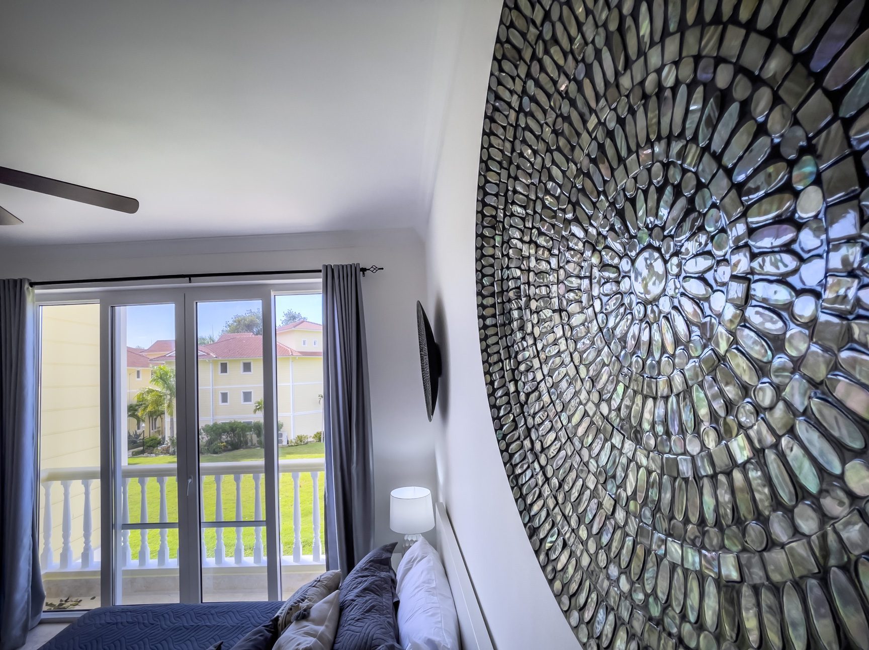 buyDRproperty Bedroom with balcony view, mosaic wall art, and neutral decor. Sosua Real Estate