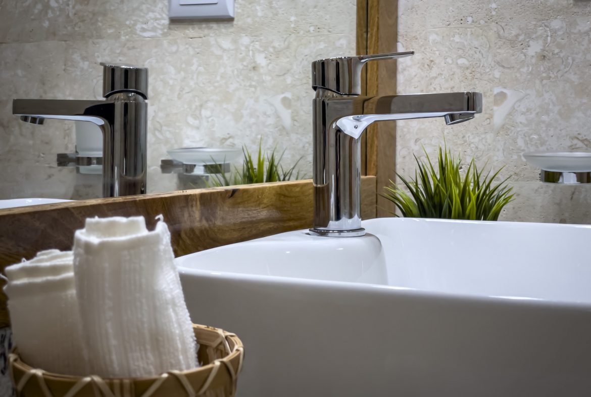 buyDRproperty Modern bathroom sink with chrome faucet, white towels, and neutral tile backdrop. Sosua Real Estate