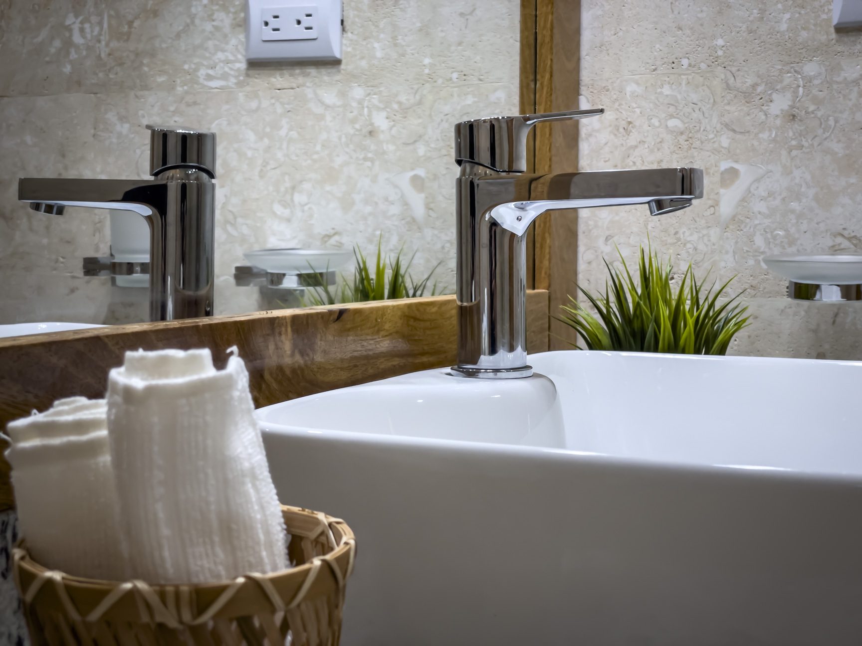buyDRproperty Modern bathroom sink with chrome faucet, white towels, and neutral tile backdrop. Sosua Real Estate