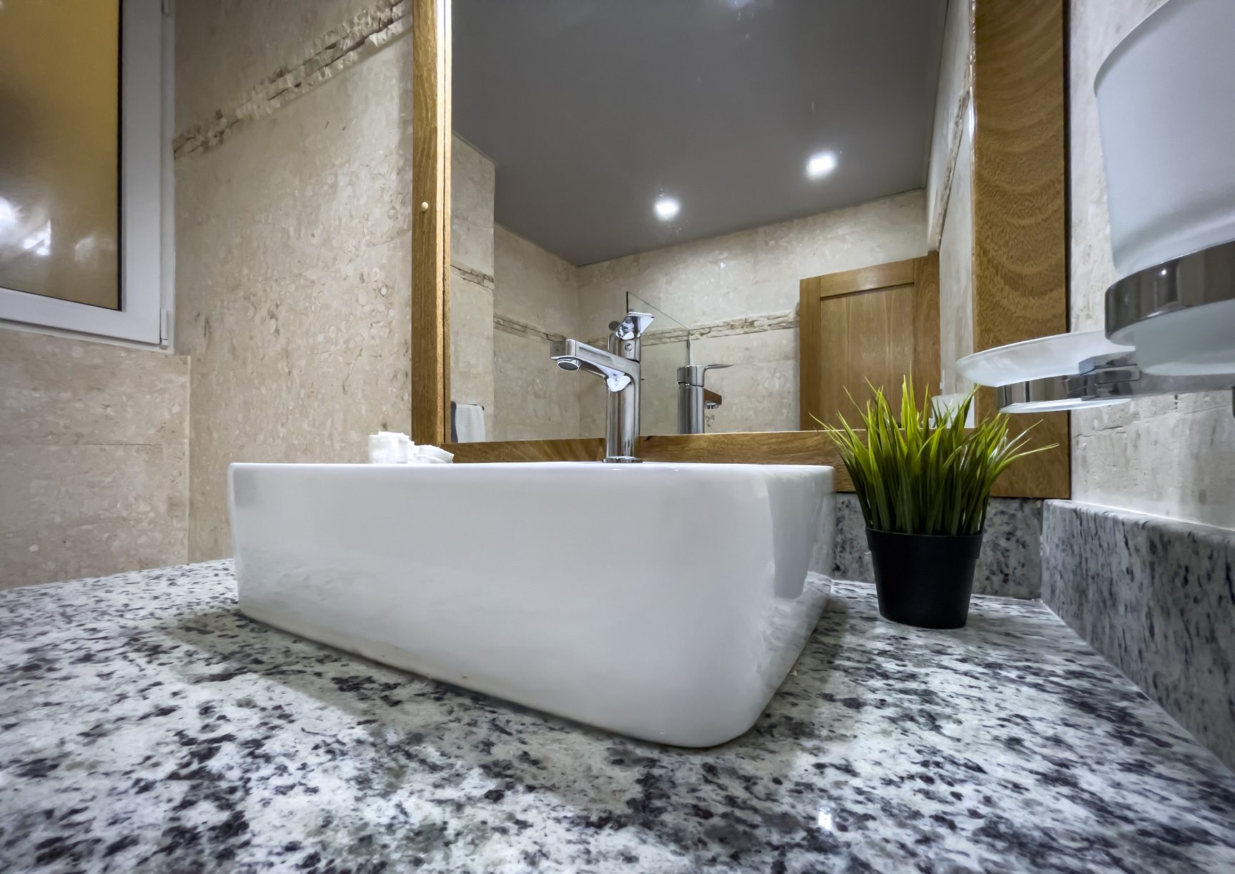 buyDRproperty Modern bathroom with white sink on granite countertop, reflecting in mirror. Sosua Real Estate