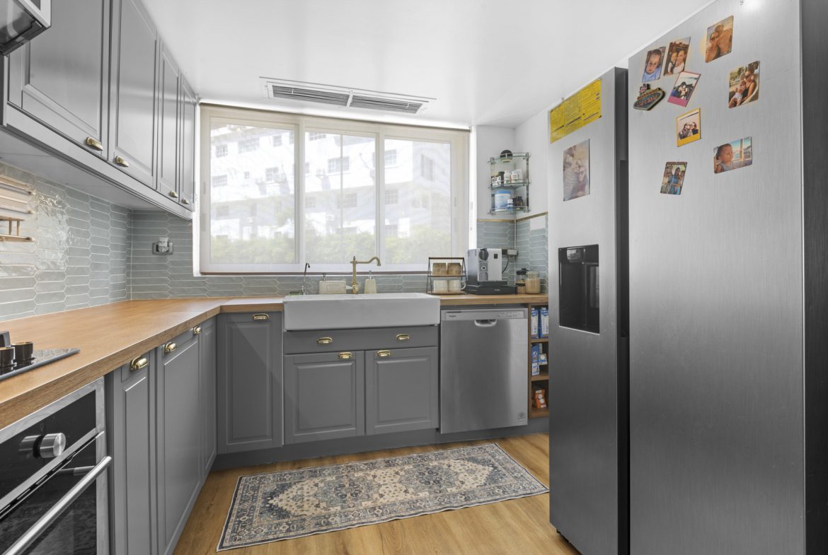 buyDRproperty Gray kitchen with wood countertops, stainless steel appliances, and a patterned rug. Bright, modern design. Sosua Real Estate