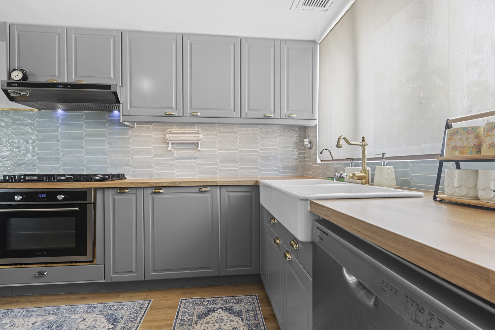 buyDRproperty Gray kitchen with farmhouse sink, butcher block countertops, and blue tile backsplash. Sosua Real Estate