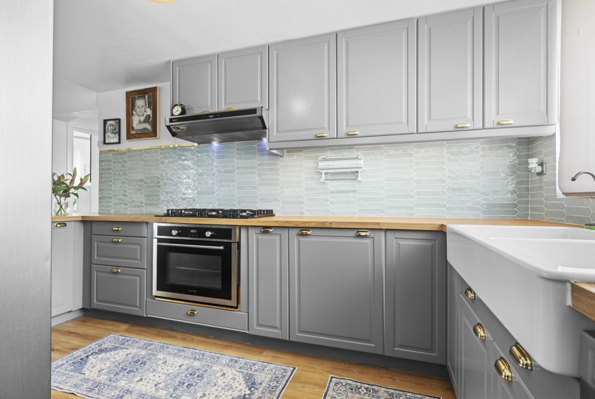 buyDRproperty Gray kitchen with wood countertops, farmhouse sink, oven, and blue backsplash. Sosua Real Estate
