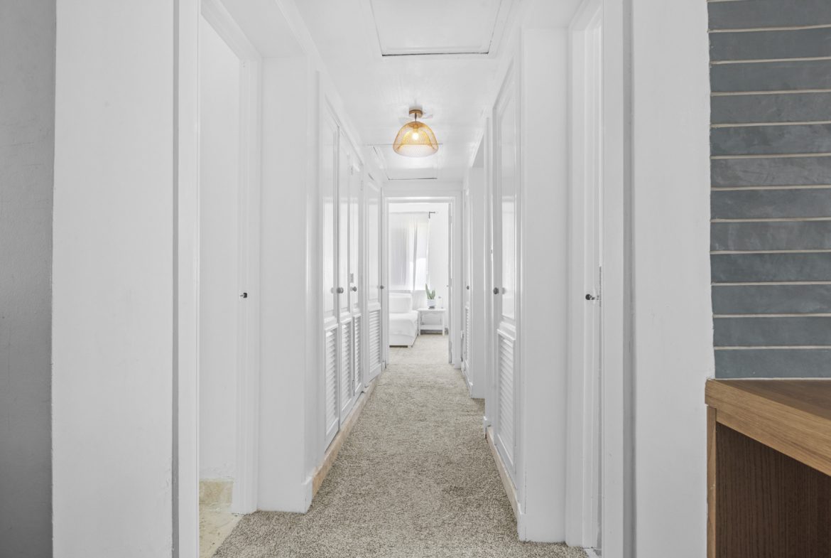 buyDRproperty Bright hallway with white walls, closet doors, and beige carpet. A warm, inviting space. Sosua Real Estate