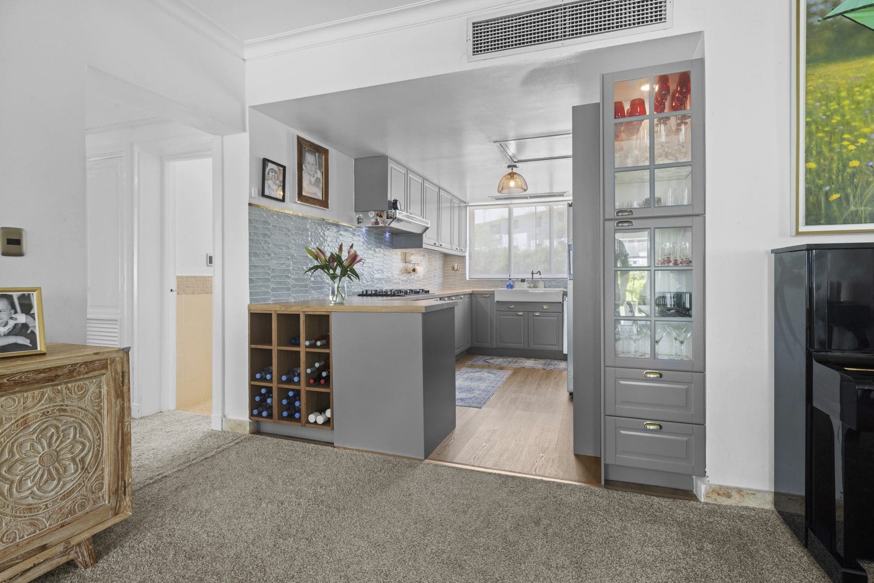 buyDRproperty Gray kitchen with wine rack, glass cabinets, and blue backsplash. Interior design. Sosua Real Estate
