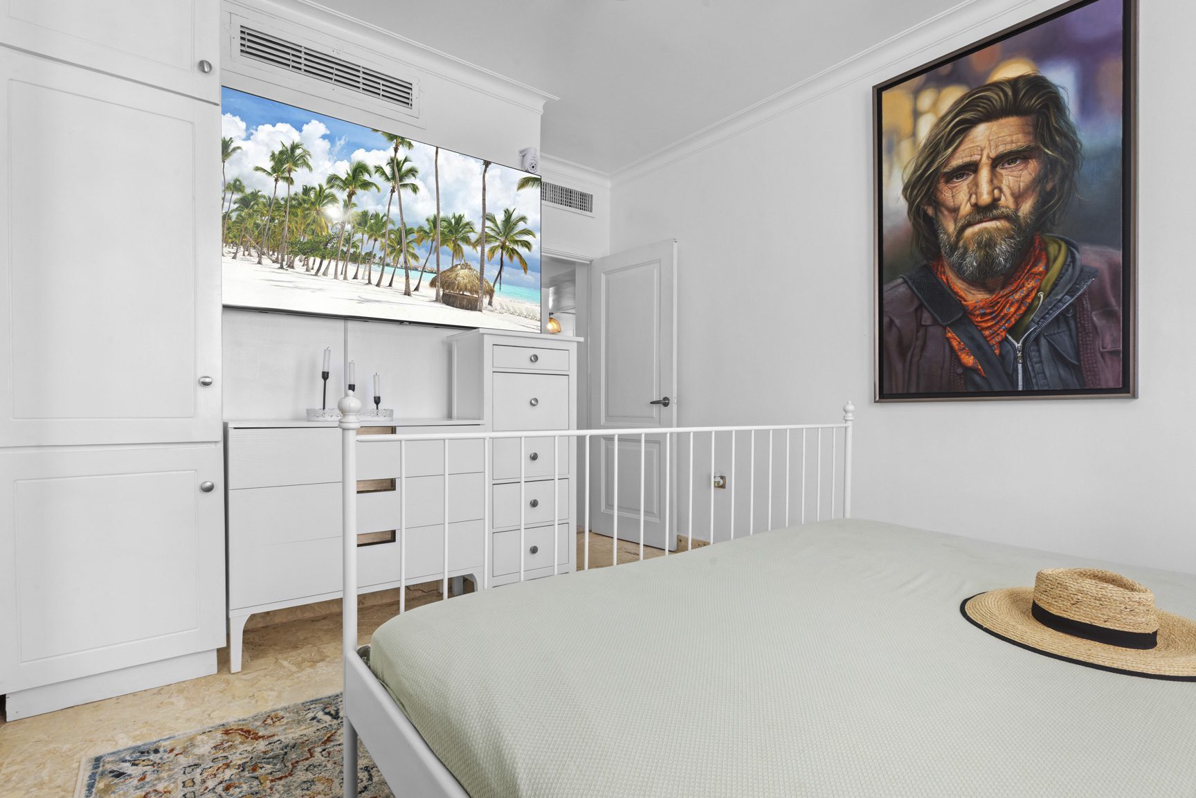 buyDRproperty Bedroom with white furniture, bed, tropical wallpaper, and a hat on the bed Sosua Real Estate