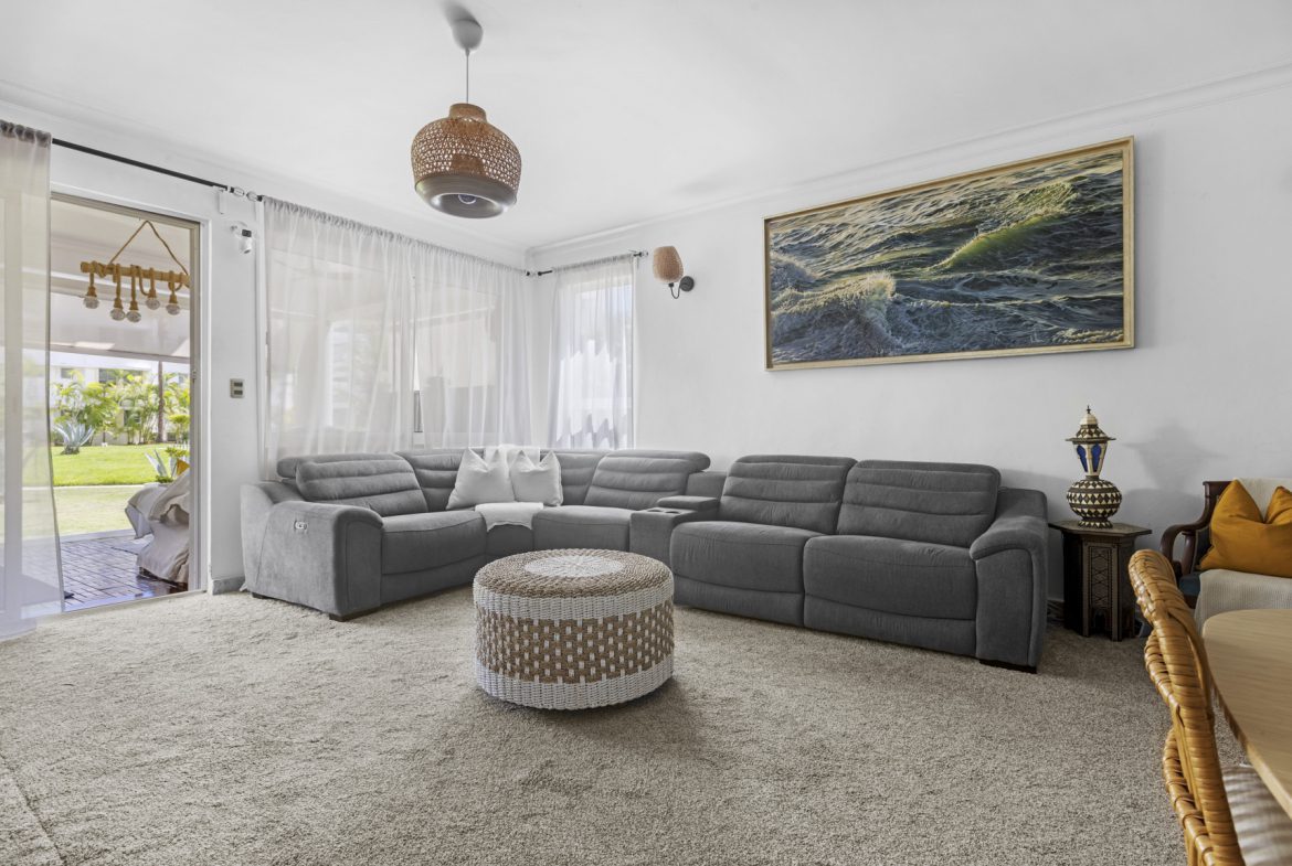 buyDRproperty Comfortable living room with gray sectional sofa and woven ottoman. Sosua Real Estate
