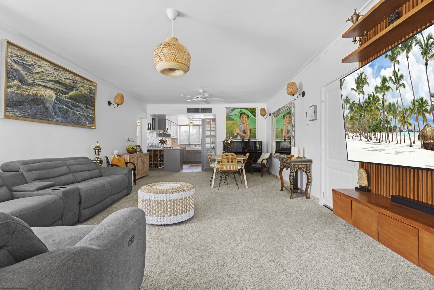 buyDRproperty Bright living room with a gray sofa, dining area, and beach scene on TV. Sosua Real Estate