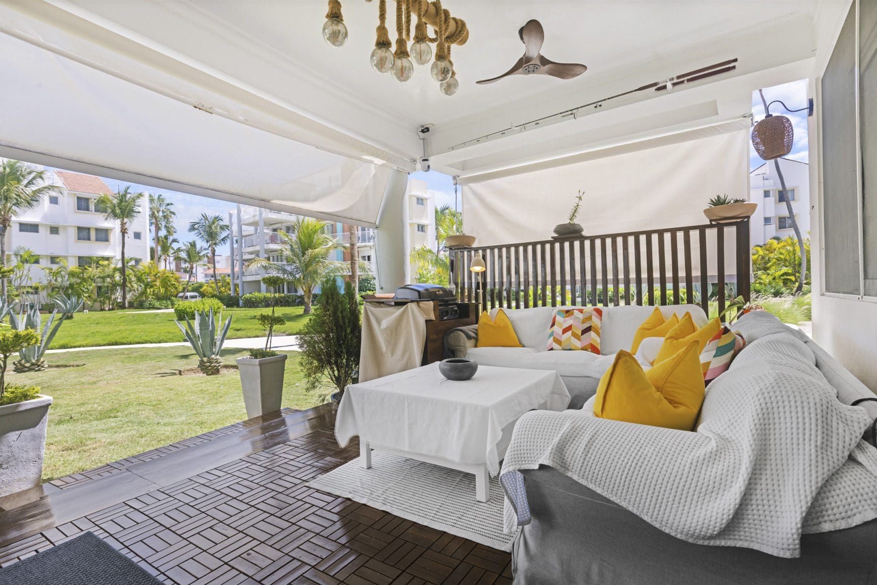 buyDRproperty Covered outdoor patio with white sofa, colorful pillows, and garden view. Sosua Real Estate