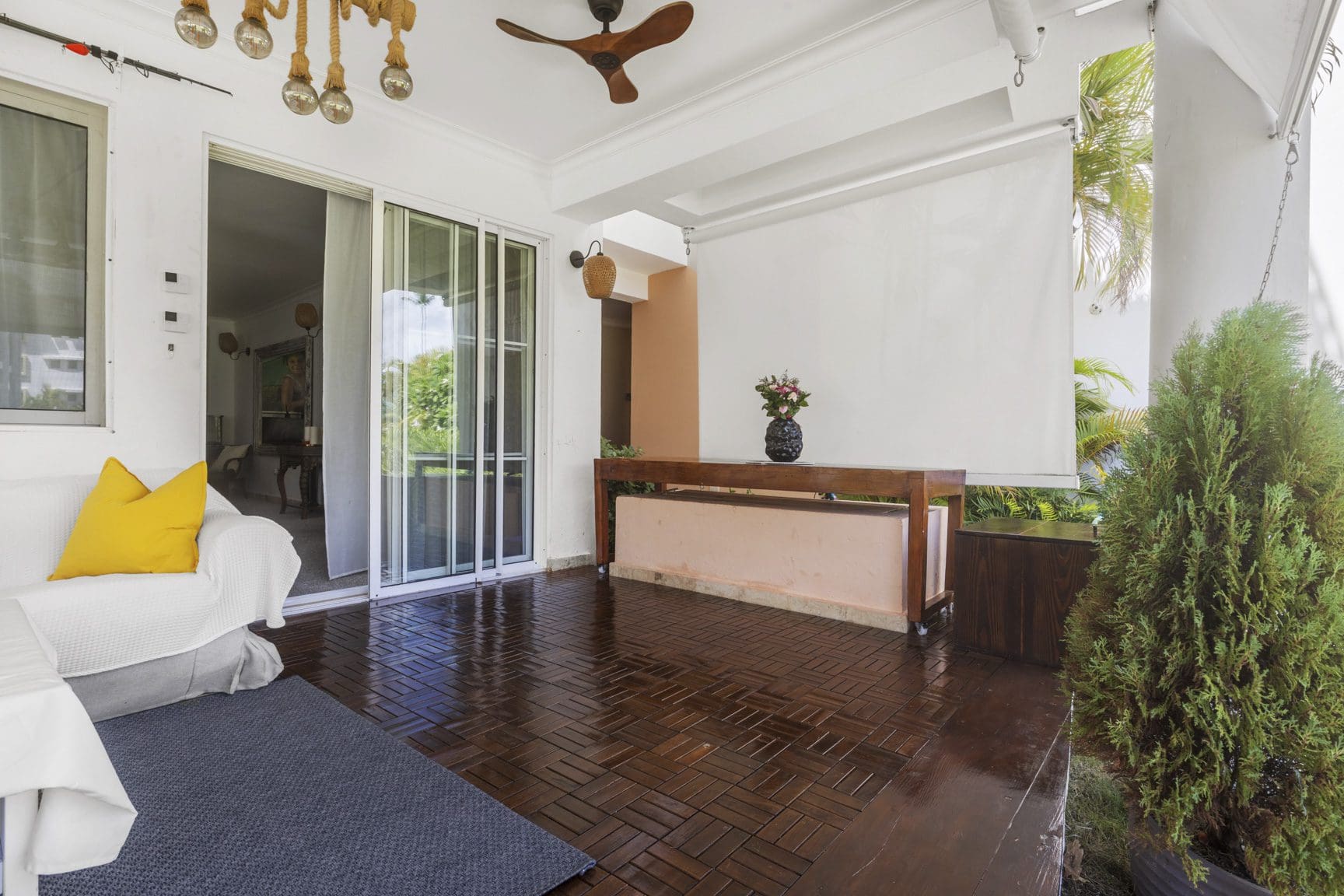 buyDRproperty Covered patio with dark wood flooring, white sofa, console table with flowers, and sliding glass doors. Sosua Real Estate