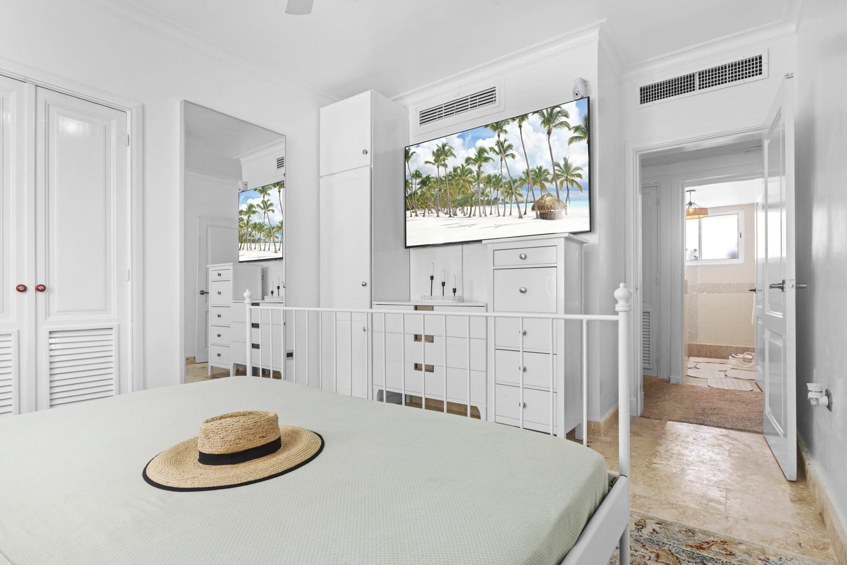 buyDRproperty Bright bedroom with beach scene on TV, hat on bed. Sosua Real Estate