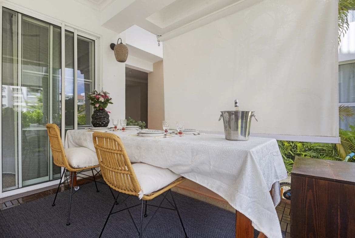 buyDRproperty Elegant outdoor dining setup with wicker chairs, white tablecloth, and wine cooler on a patio. Sosua Real Estate